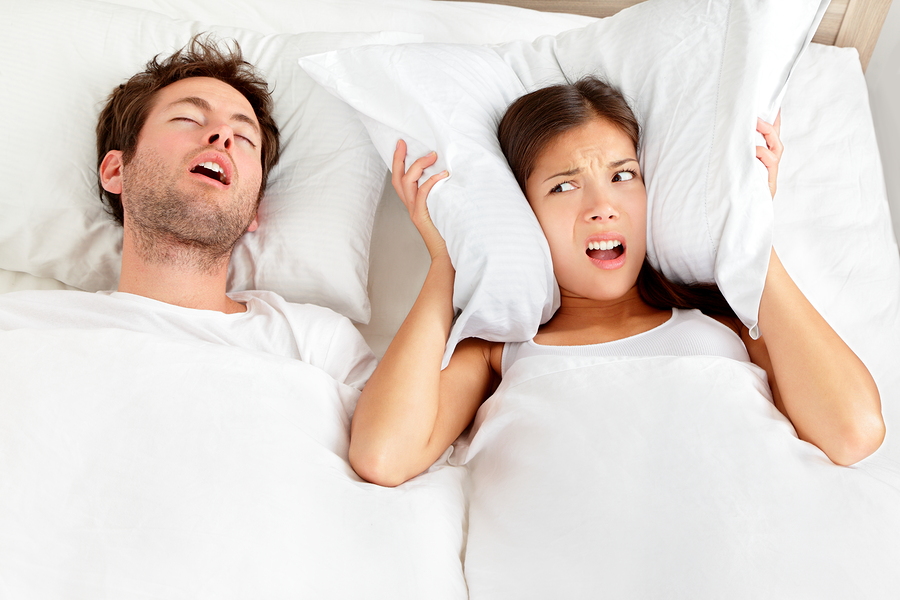 woman holding pillow over ears next to snoring husband, Troy, NC sleep apnea therapy